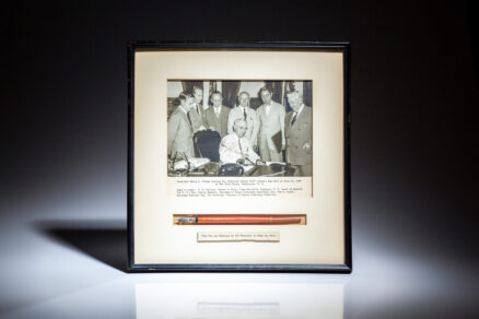 Signed photograph of President Harry S. Truman signing the "Judicial Salary Bill" on July 31, 1946, with the pen used to sign the bill mounted below photograph. From the estate of Assistant Attorney General H. Graham Morison.