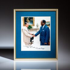 Signed photograph of President Ronald Reagan and the United States Ambassador to South Africa, Edward J. Perkins. Signature of Ronald Reagan is autopen.